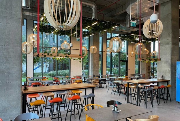 Restaurant decorat in stil industrial avand corpuri de iluminat cu led personalizate ce scot in evidenta culorile vibrante de galben si portocaliu din zona meselor