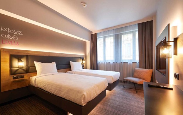 Camera de hotel cu paturi individuale amenajata folosind corpuri de iluminat cu led subtile ce confera caldura spatiului